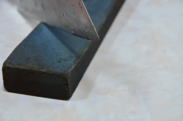Lâmina de faca de cozinha em pedra de amolar — Fotografia de Stock