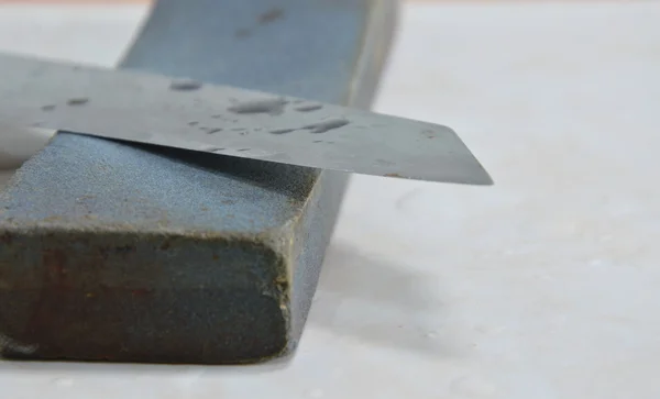 Lâmina de faca de cozinha e pedra de amolar no chão da telha — Fotografia de Stock