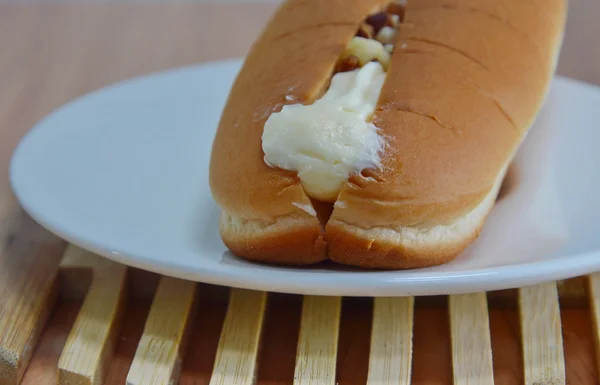 Pão de cachorro quente cheio de creme e amêndoa em prato de madeira — Fotografia de Stock