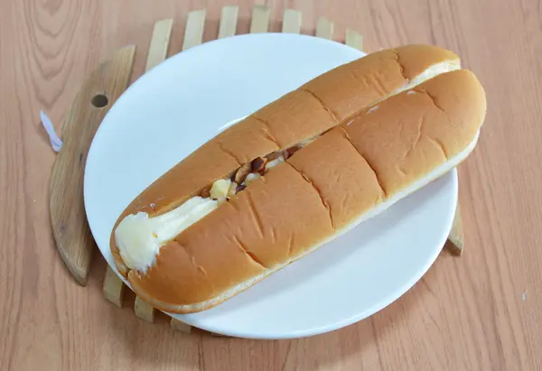 Hot dog bread filled cream and almond on wooden dish plate — Stock Photo, Image