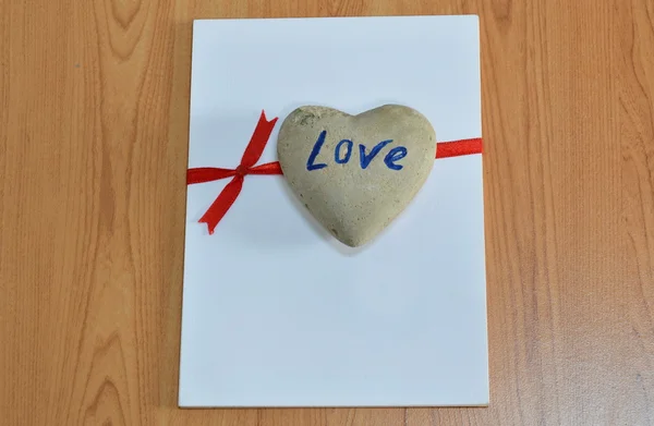 Heart rock on white paper tie red ribbon — Stock Photo, Image