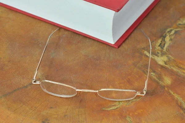 Gold frame eyeglass and red book — Stock Photo, Image