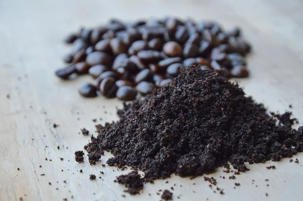 Grano de café tostado oscuro y polvo sobre tabla de madera — Foto de Stock