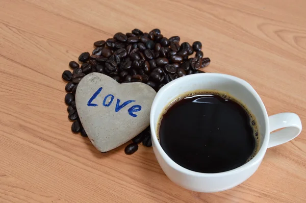 Taza de café negro y frijol con piedra corazón — Foto de Stock