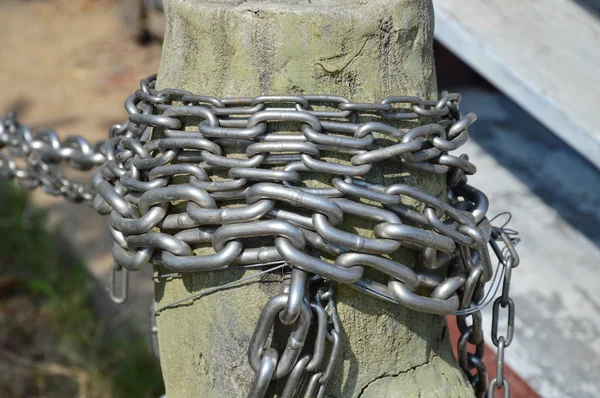 Rollo de cadena de metal sobre poste de madera — Foto de Stock