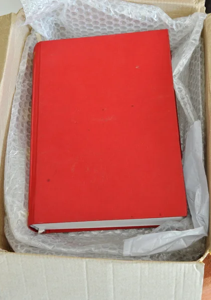 Libro rojo en caja de papel marrón —  Fotos de Stock