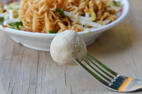 Bola de cerdo apuñalada en tenedor y fideos instantáneos hervidos en el plato —  Fotos de Stock