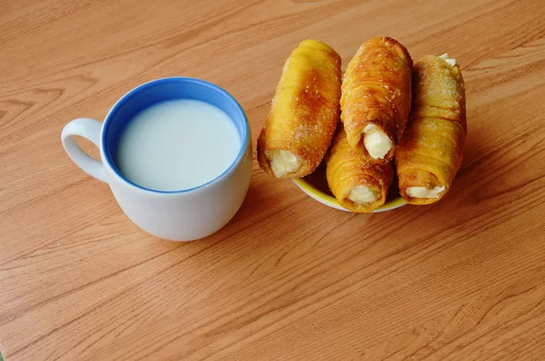 Pão creme de enchimento rolo e xícara de leite na mesa — Fotografia de Stock