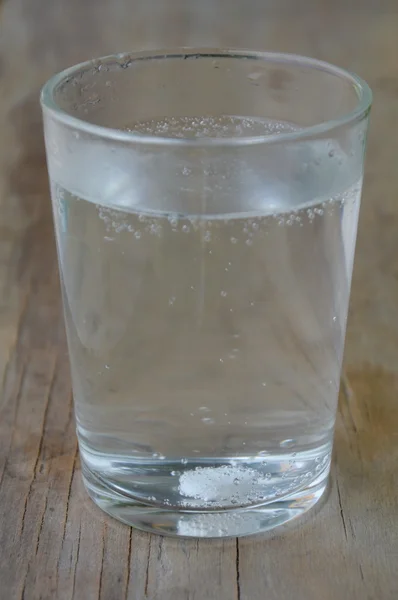 Antazida im Wasserglas auf Holztisch — Stockfoto