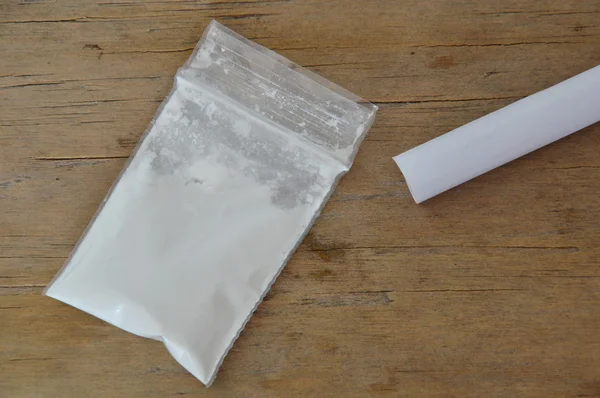 Cocaïne in plastic hersluitbare zak en papierrol op houten bord — Stockfoto