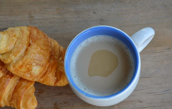 Croissant manteiga e café com leite em tábua de madeira — Fotografia de Stock
