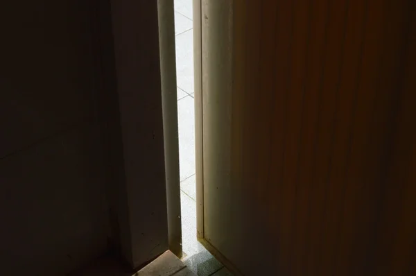 Cahaya menyaring keluar dari pintu ajar dalam gelap — Stok Foto