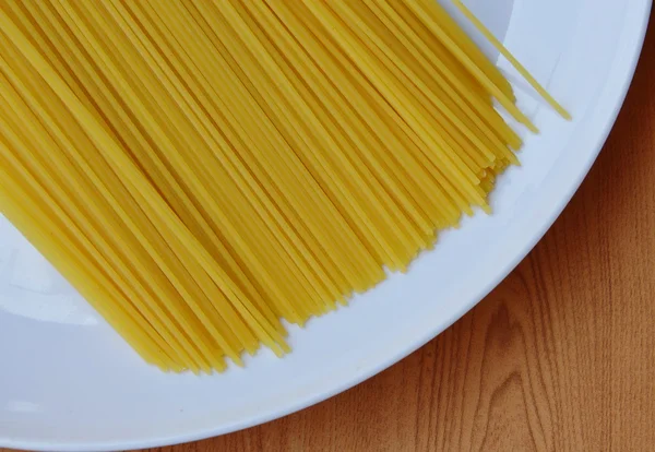 Torkade spaghetti på vit platta — Stockfoto