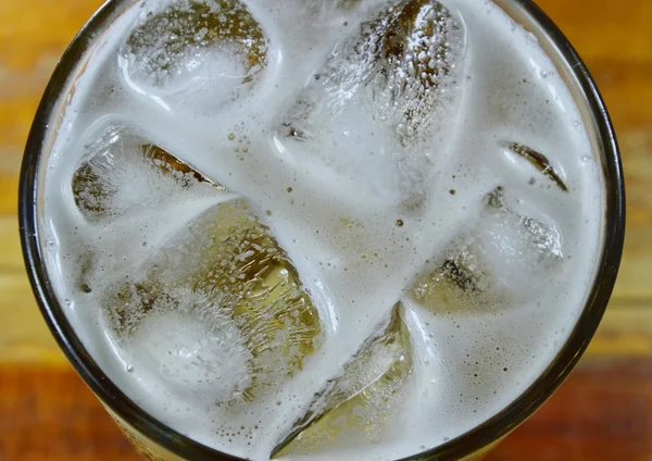 Cerveza y hielo en vaso sobre la mesa — Foto de Stock