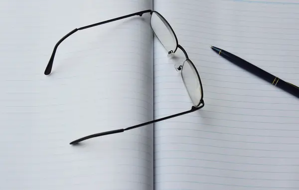 Gözlük camı ve kalem kitap — Stok fotoğraf