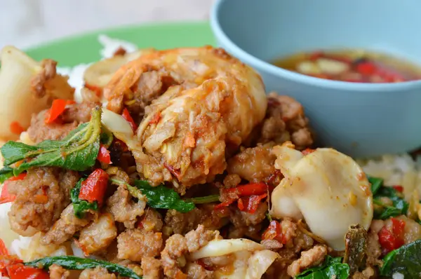 Pedas aduk-goreng makanan laut campuran dan memotong babi dengan daun kemangi pada beras — Stok Foto