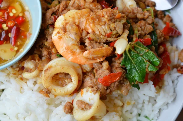 Pedas aduk-goreng makanan laut campuran dan memotong babi dengan daun kemangi pada beras — Stok Foto
