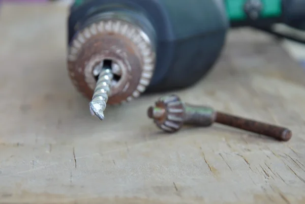 Taladro eléctrico y llave de mandril en tablero de madera —  Fotos de Stock