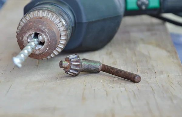 Taladro eléctrico y llave de mandril en tablero de madera —  Fotos de Stock