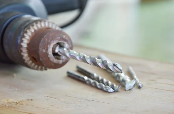 Taladro eléctrico y diverso tamaño de bit en tablero de madera —  Fotos de Stock