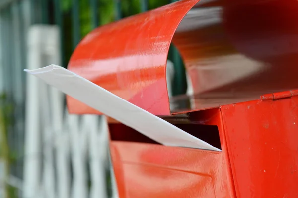 Witte envelop in rode brievenbus op home hek — Stockfoto