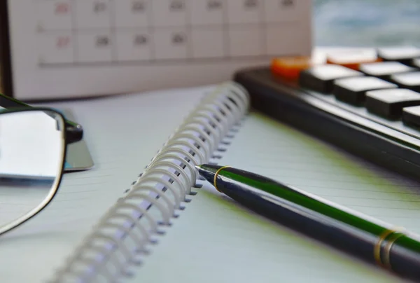 Pen en calculator op het boek — Stockfoto