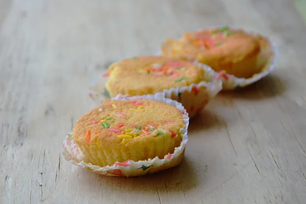 Butter cupcake dressing colorful candy in paper on wooden board — Stock Photo, Image