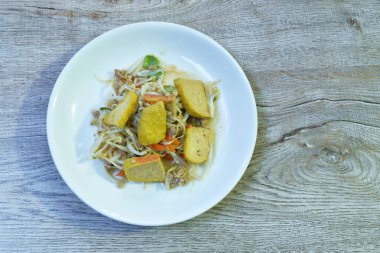 Kızarmış fasulye filizi, dilimlenmiş sarı tofu ve masada domuz pirzolası.