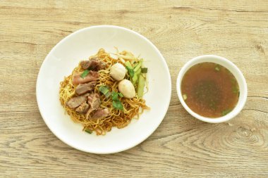 Çin usulü sarı erişteli domuz eti ve tabakta kemik ve kahverengi bitki çorbası fincanı.