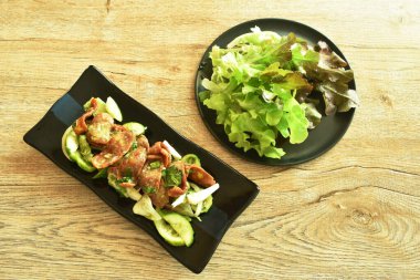 Baharatlı kızarmış Çin domuz sosisi, salatalık ve soğanlı Tayland salatası. Tabakta taze sebze yiyin.