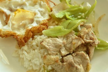 Kızarmış domuz eti, uzun biber dilimi ve tabakta soğan soslu pirinç çifti.