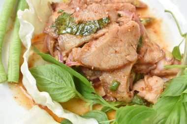 Baharatlı domuz etli Tayland salatası taze fesleğen yaprağı ve lahana ile yenir.