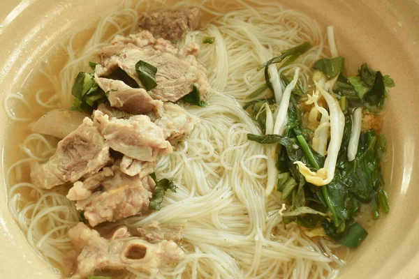 Haşlanmış vermicelli ince pirinç eriştesi üzerine fırında pişmiş domuz eti kasede kahverengi sebze çorbası.