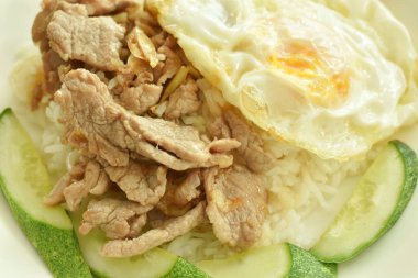 Kızarmış domuz eti, sarımsak ve biberli yumurta, sade pirinç tabağında.