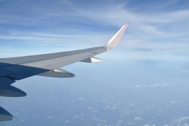 Pencere çerçevesinden gökyüzünde süzülen kanat ve bulut