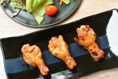  Kızarmış tavuk kanadı, barbekü sosu ve sebze tabağı.