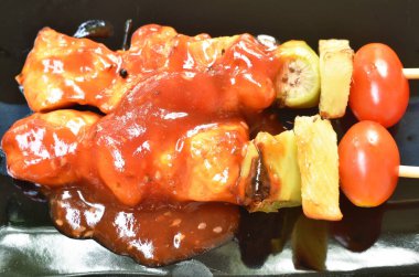  Ananaslı kızarmış tavuk ve domates soslu barbekü tabağa tahta sopa saplıyor.