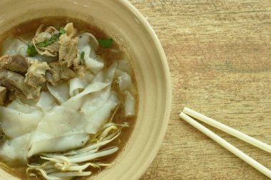  Büyük pirinç eriştesi dilimlenmiş domuz eti kasede kahverengi sebze çorbası.