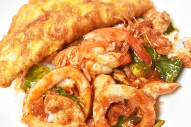  Baharatlı kızarmış karides ve et soslu kalamar körisi tabakta Tayland yumurtalı omlet.