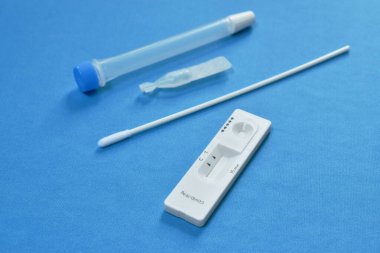  Mavi kumaş arka planında COVID-19 veya koronavirüs kontrolü için antijen test kiti