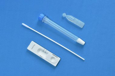  Mavi kumaş arka planında COVID-19 veya koronavirüs kontrolü için antijen test kiti