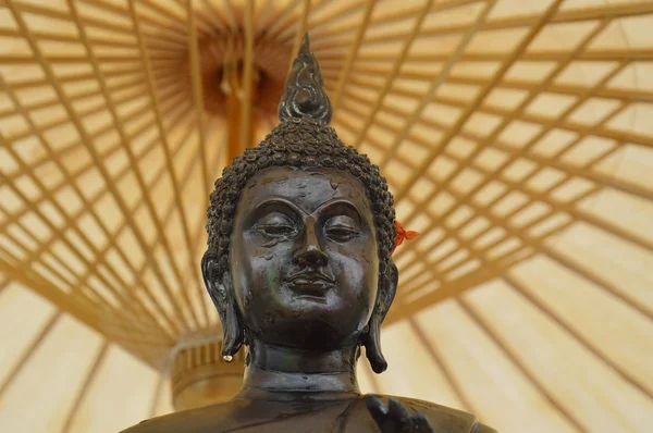 Strooi water op een Boeddha onder paraplu — Stockfoto