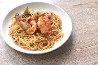 spicy fried vegetarian Chinese yellow rice noodles with shrimp and squid couple chili basil on plate
