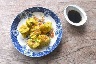 steamed yellow Chinese dumpling filling mashed pork and shrimp or dim sum topping parsley on plate dipping sour soy sauce 