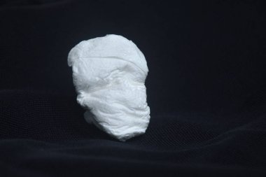 Beyaz doku siyah kumaş arka planında insan yüzü gibi görünüyor.