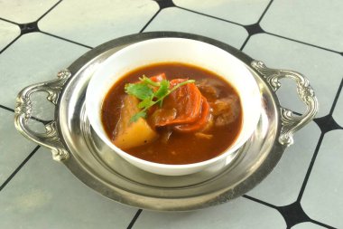 Kaynamış tavuk havucu ve patates. Tabakta kırmızı sos güveci. 