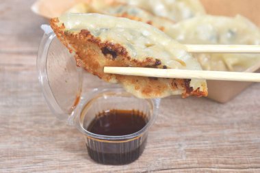 Çıtır çıtır kızarmış Gyoza ya da içi doldurulmuş Japon köftesi doldurulmuş domuz püresi ahşap çubuklu Shoyu sosu.