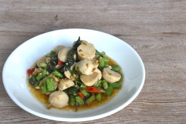 Baharatlı, kızarmış domuz pirzolası ve köfteli, uzun fasulyeli, tabağında fesleğenli.