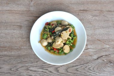 Baharatlı, kızarmış domuz pirzolası ve köfteli, uzun fasulyeli, tabağında fesleğenli.