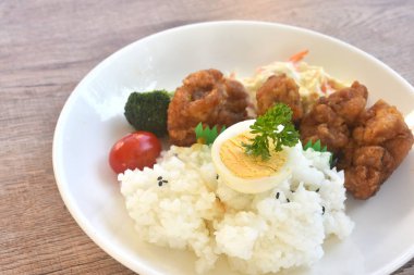 Kızarmış sarımsaklı tavuk, haşlanmış yumurta, siyah susamlı pilav ve tabakta salata.